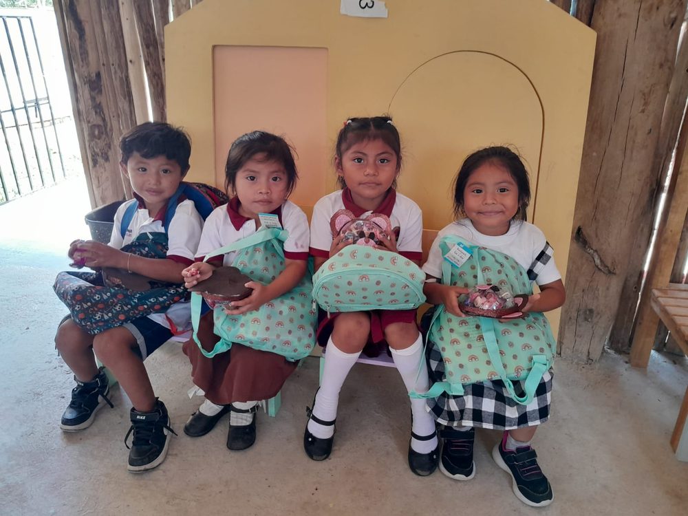 Niñas y niños de una comunidad maya con sus mochilas nuevas